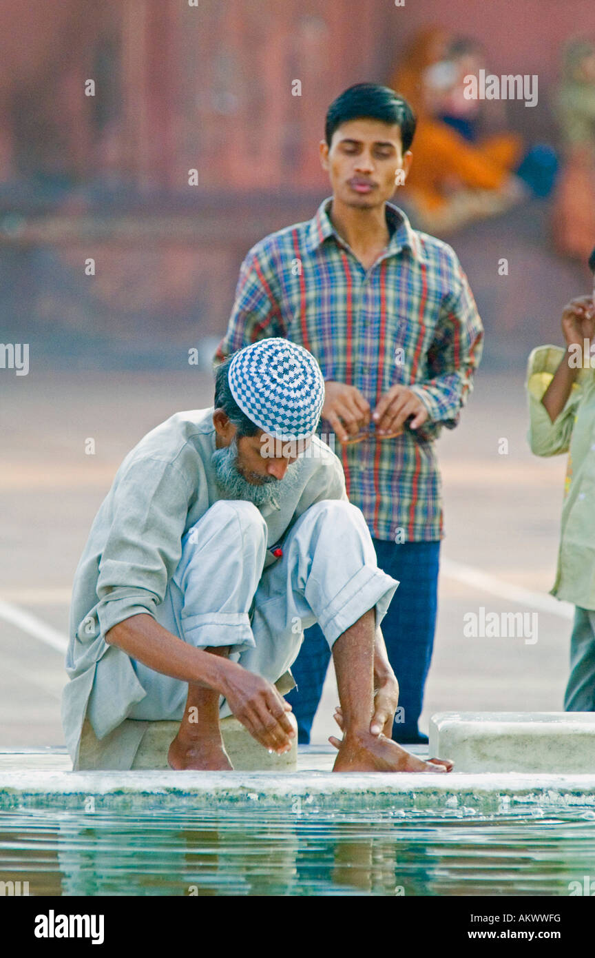 A Muslim man washes his feet in the fountain at the Jama Masjid mosque in Old Delhi, India. - Stock Image