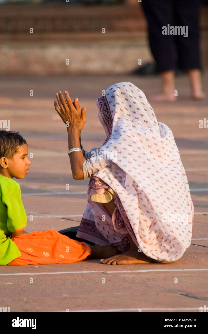 A Muslim grandmother sites with her grandsons in the massive courtyard of the Jama Masjid mosque in Old Delhi, India. - Stock Image