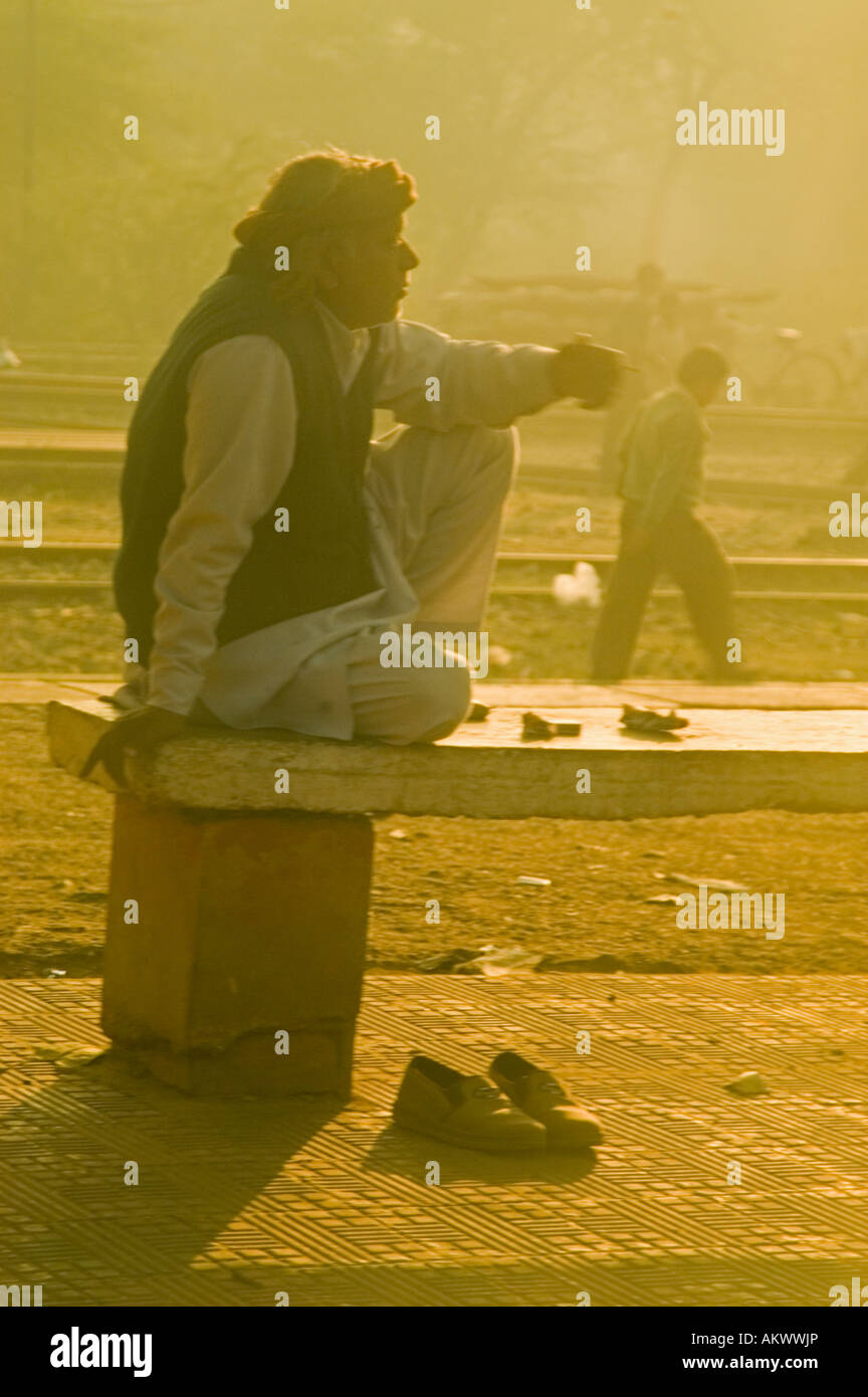 An Indian man sips his morning chai tea at a train station at sunrise on the outskirts of New Delhi, India. - Stock Image
