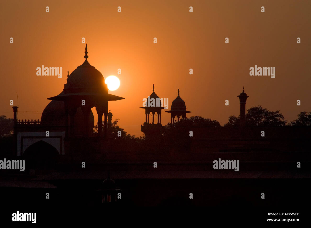 The guard towers of Agra's Red Fort are silhouetted against the setting sun in Agra, Uttar Pradesh, India. - Stock Image