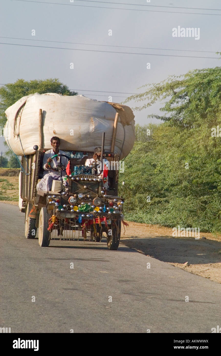 Men drive a ramshackle vehicle full of cotton down the road to the village of Bhandarej, Rajasthan, India. - Stock Image