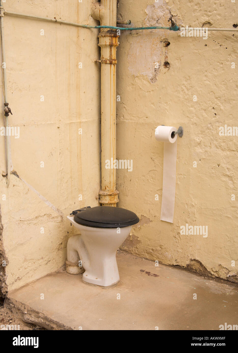 Corner of an old outdoor toilet half demolished with only two walls