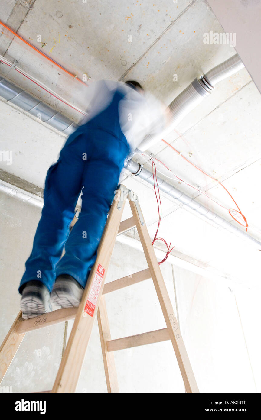 Construction worker lays cables at the ceiling Stock Photo