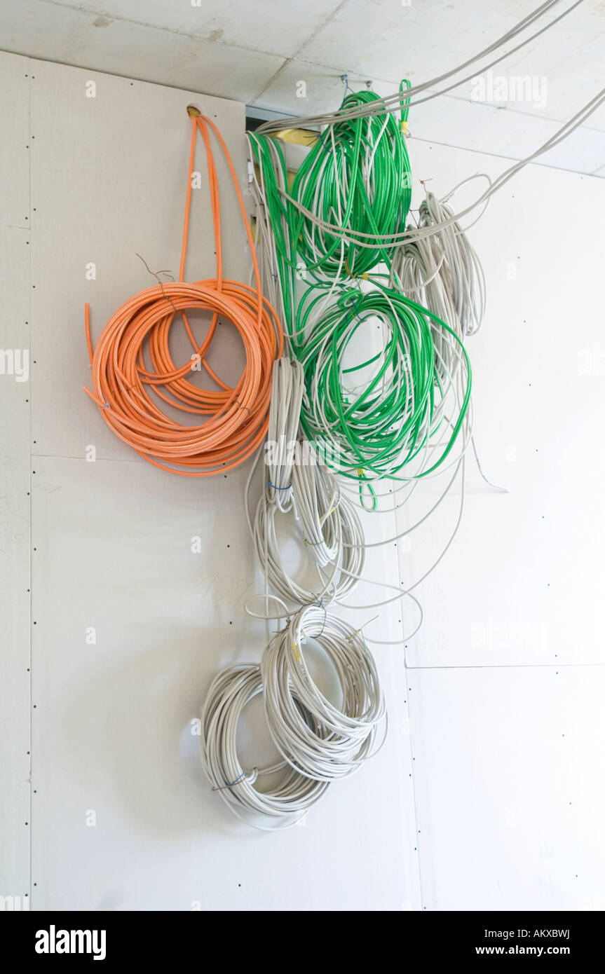 Cables hang down from a wall Stock Photo