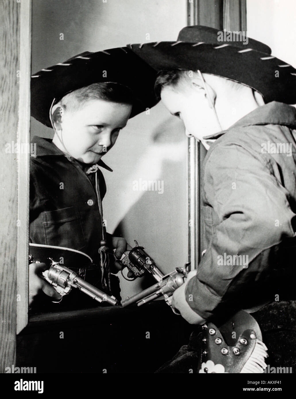 young-boy-in-cowboy-suit-pondering-his-image-in-mirror-1950-s-AKXF41.jpg
