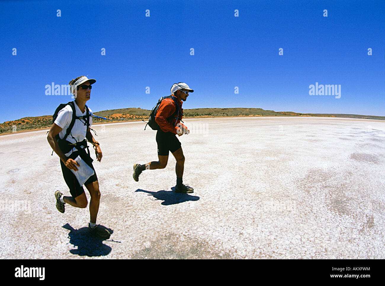 Sam Gehring and Darran Wells run across a salt pan in South Africa's Kalahari Desert as part of a reality TV - Stock Image