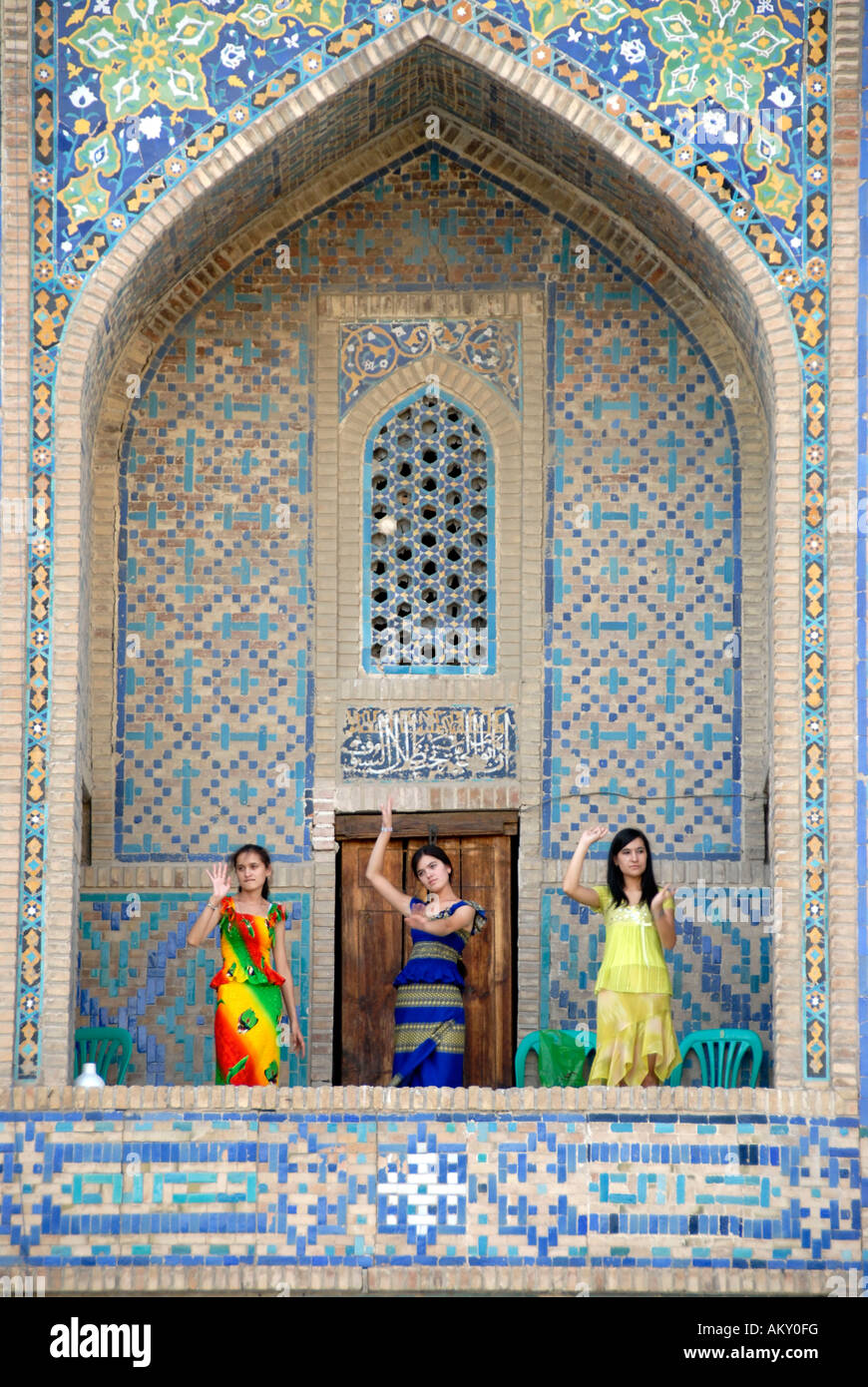 Young women dancing in an arch of Madrasah Tilla-kari Registan Samarkand Uzbekistan Stock Photo