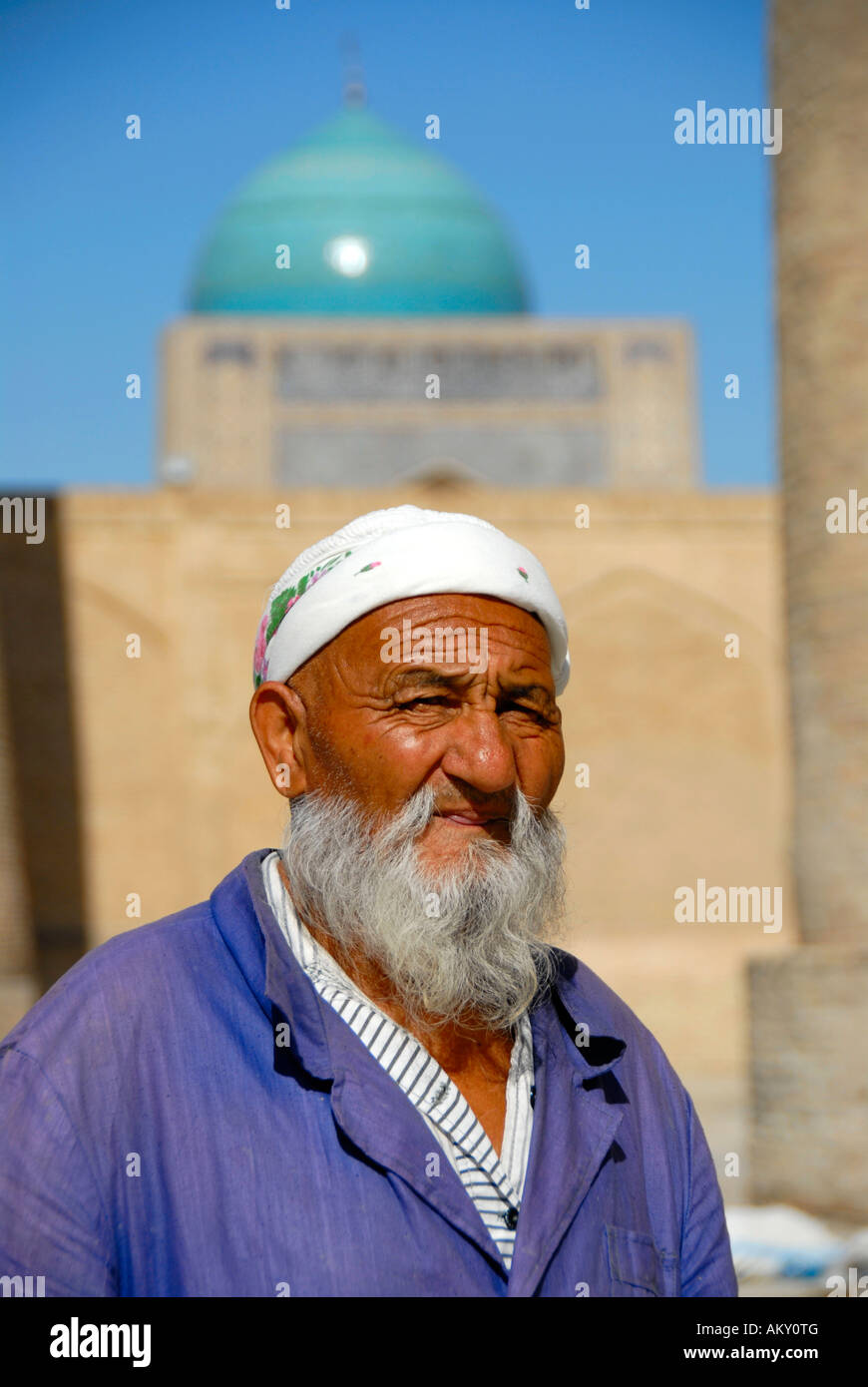 Portrait old Muslim believer with beard in front of blue cupola of Mosque Kalon Bukhara Uzbekistan Stock Photo