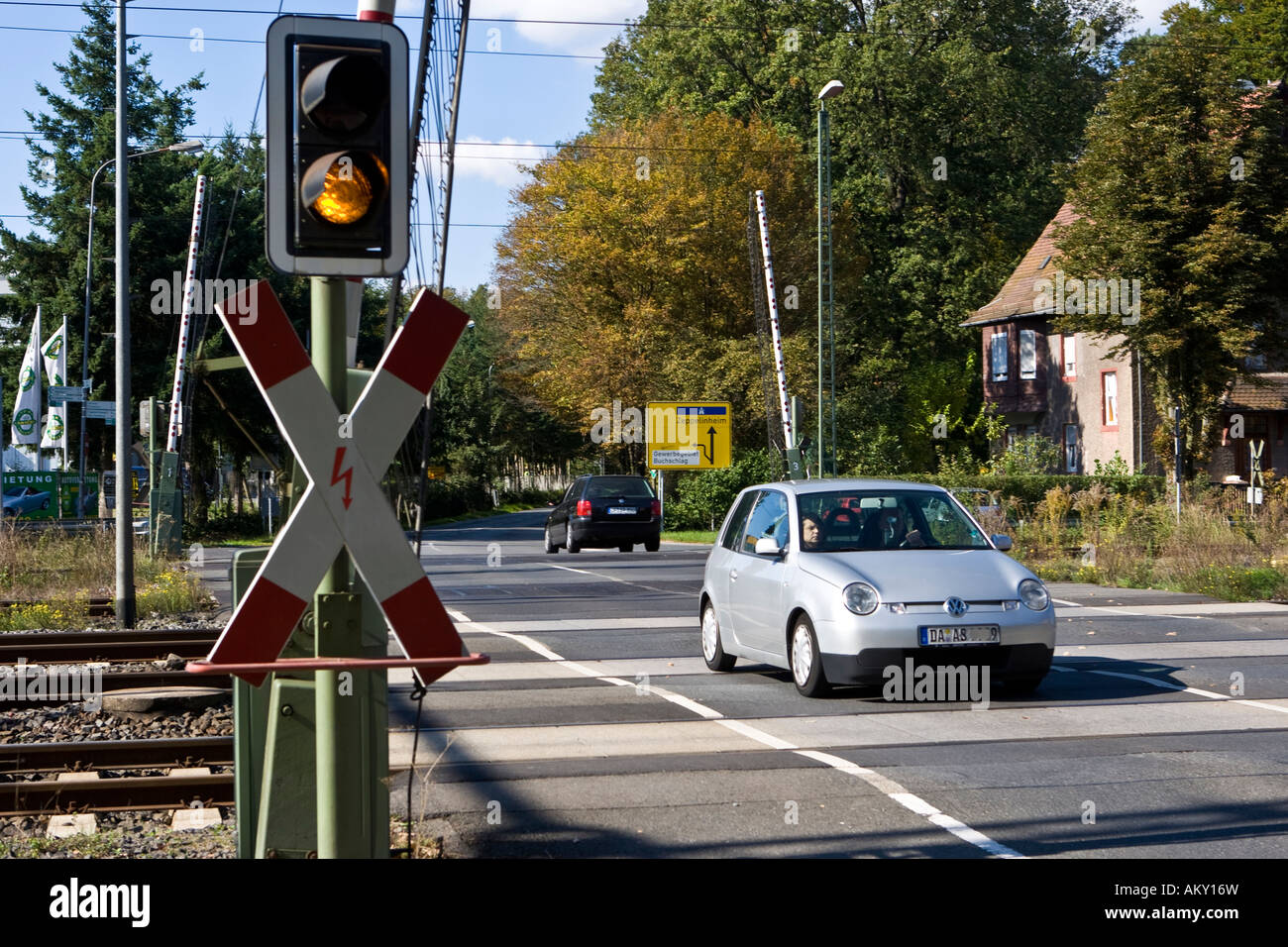 Car is driving over an railway level crossing with opened gates, with St Andrew´s Cross and yellow traffic light, Hessen, Germa Stock Photo