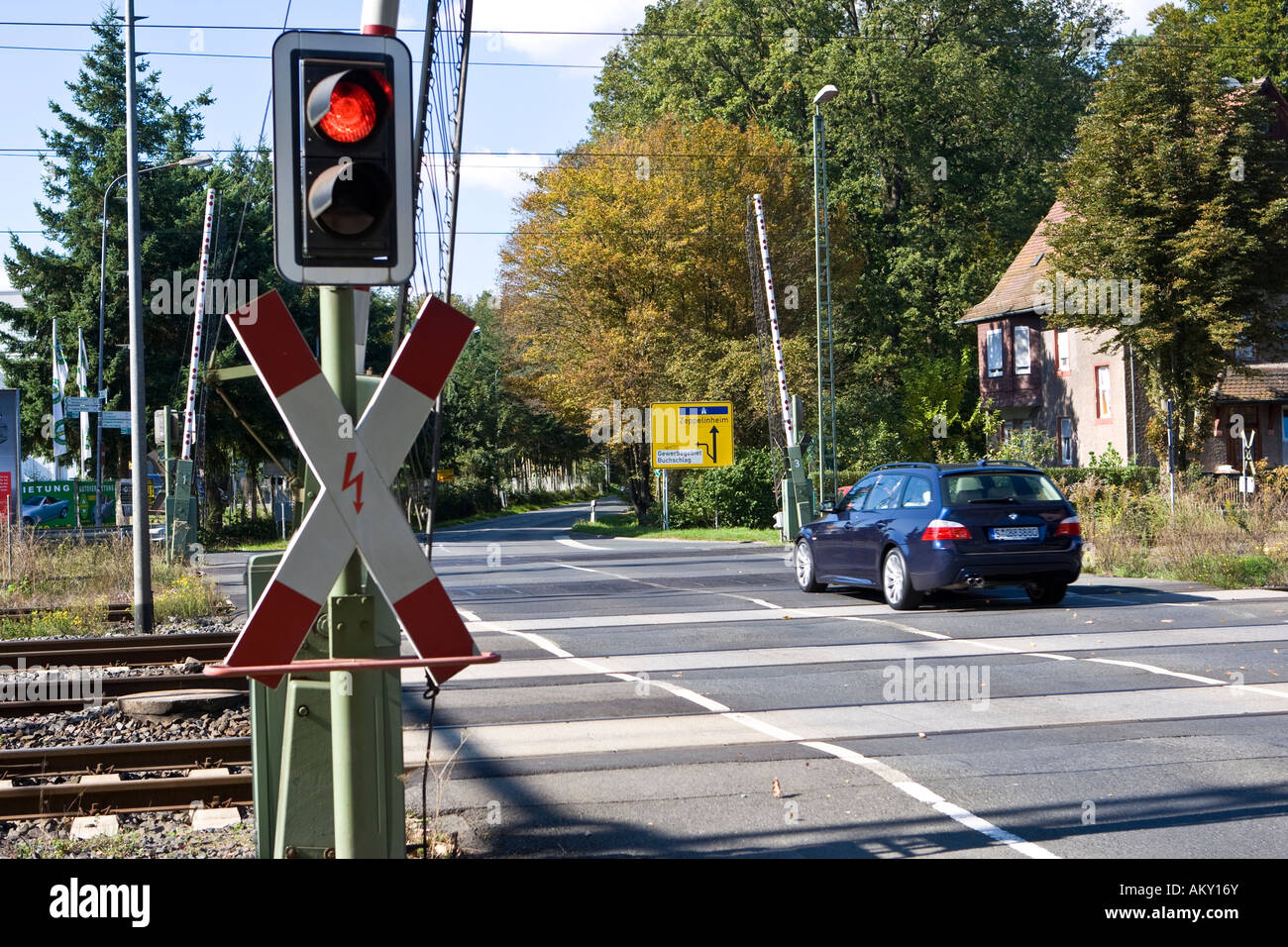Car is driving over an railway level crossing with opened gates, with St Andrew´s Cross and red traffic light, Hessen, Germany Stock Photo