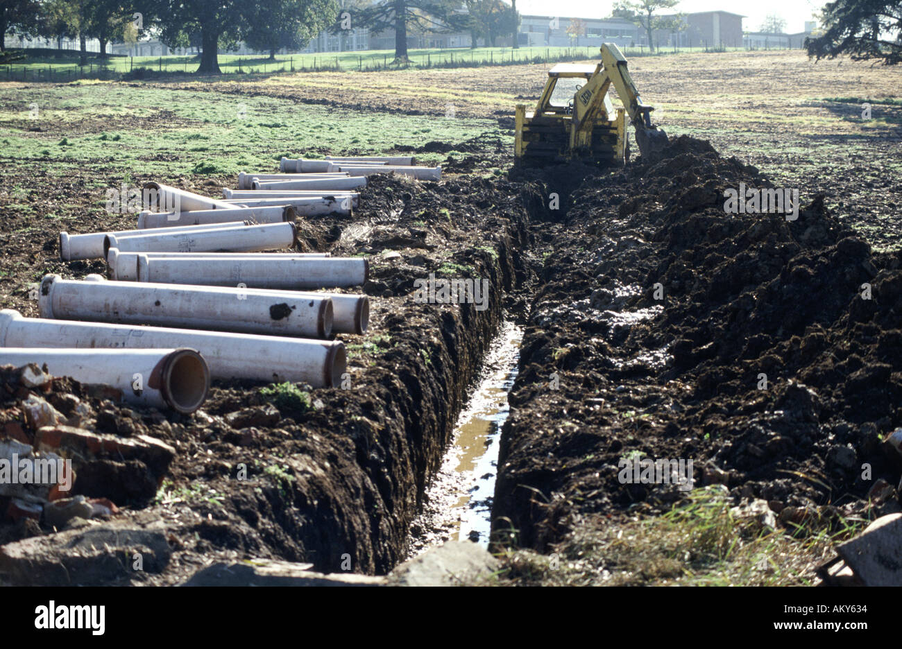 JCB Digger excavator digging trench for field drainage pipes Stock Photo