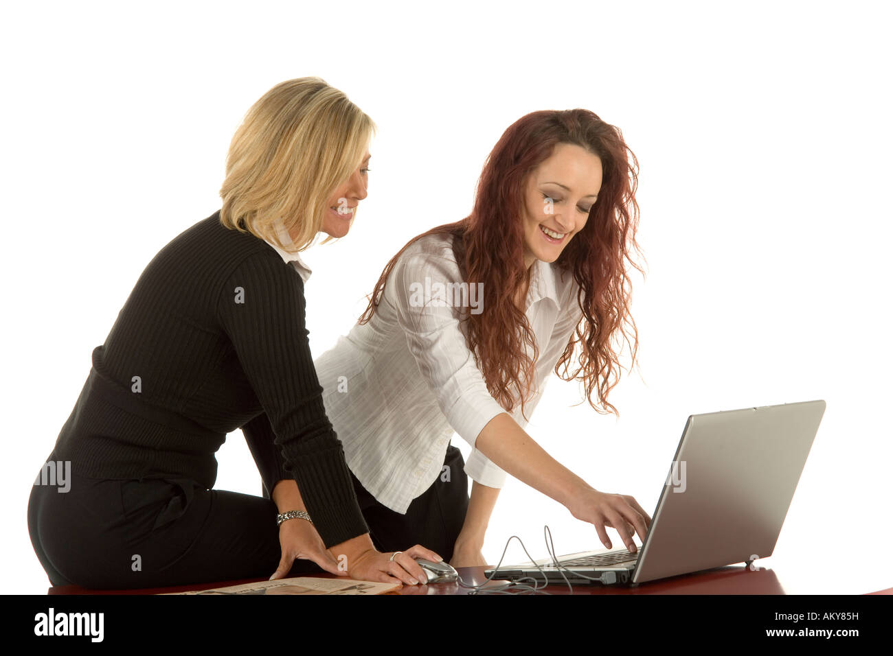 Two young businesswomen working together in an office environment on a ...