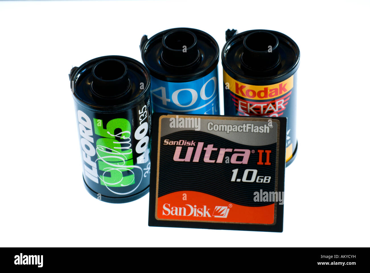 Three 35mm film cassettes and a compact flash card on a white