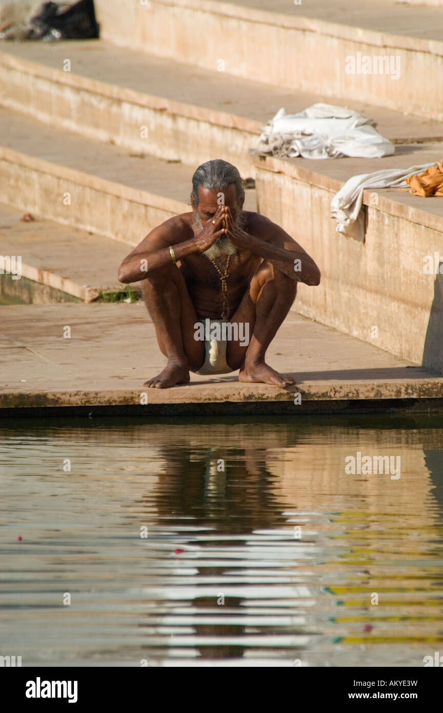 A Hindu pilgrim prays before bathing in the sacred waters of Pushkar Lake at Gangour Ghat, Pushkar, Rajasthan, India. - Stock Image