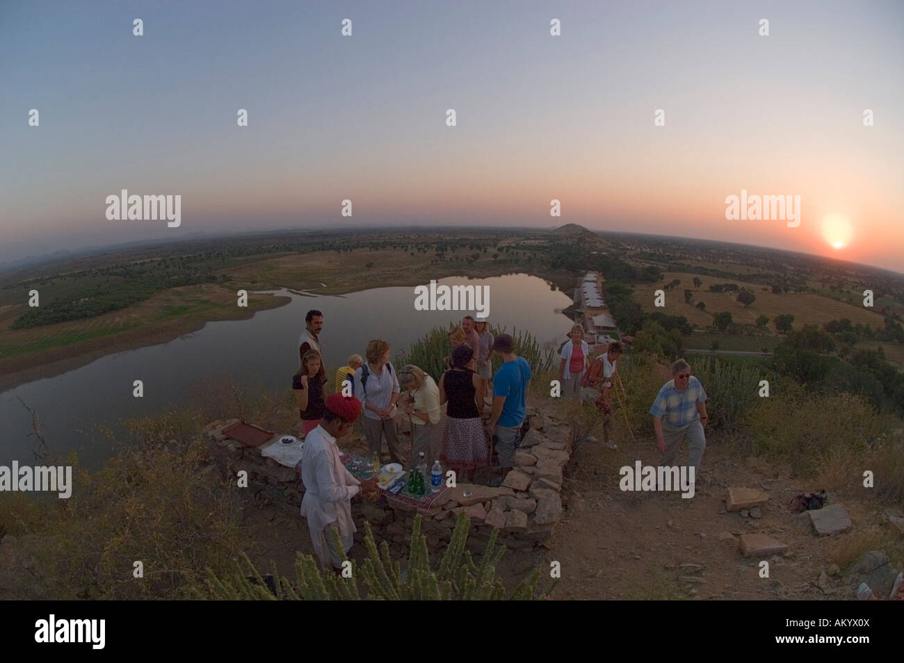 Tourists enjoy an evening gin and tonic on the hillside high above Chhatra Sagar, a deluxe eco-resort near the village - Stock Image
