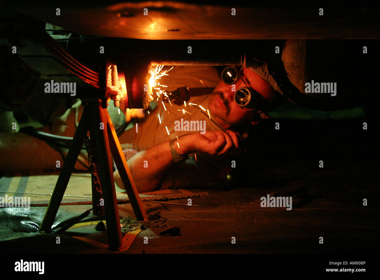 Mechanic lies under a car and is autogenous welding on a car Stock Photo