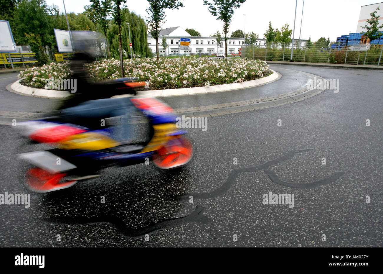 Powered two-wheeler drinving a roundabaut with dangerous paving Stock Photo