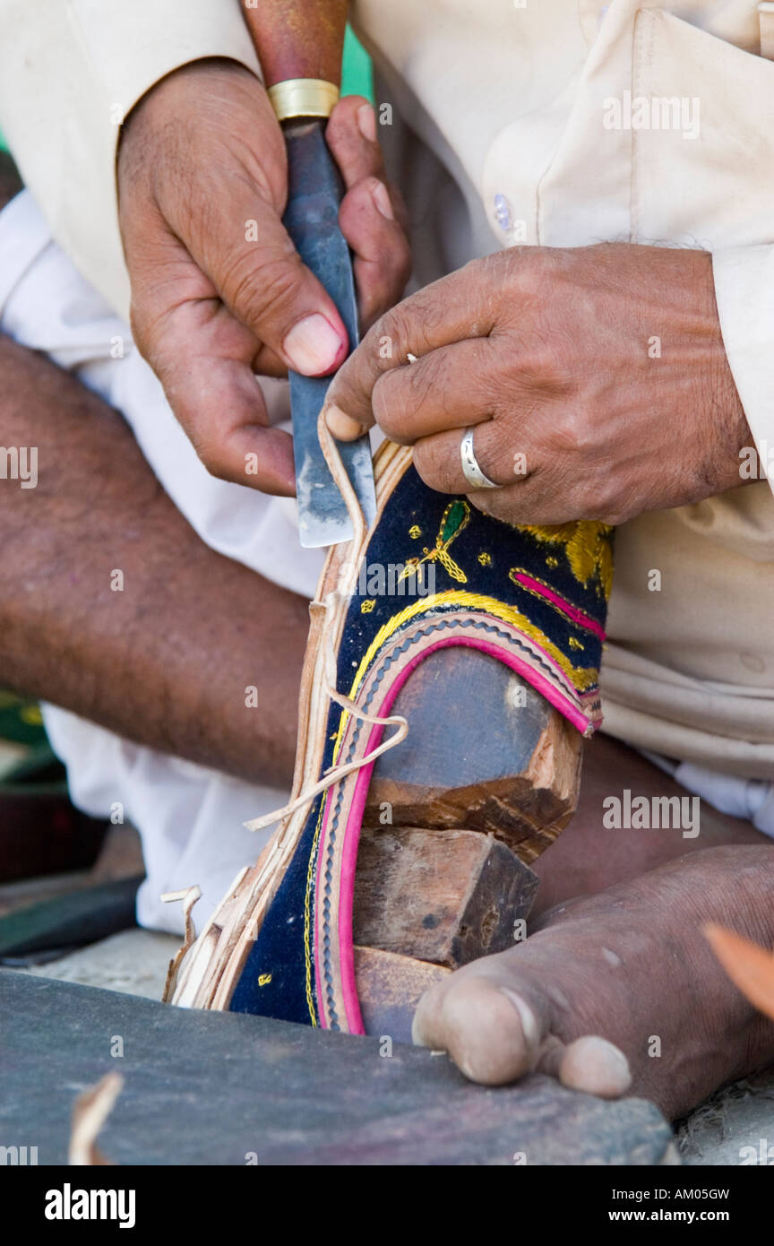 A dalit, or untouchable, cobbler makes Rajasthani shoes outside of the village of Nimaj, Rajasthan, India. - Stock Image