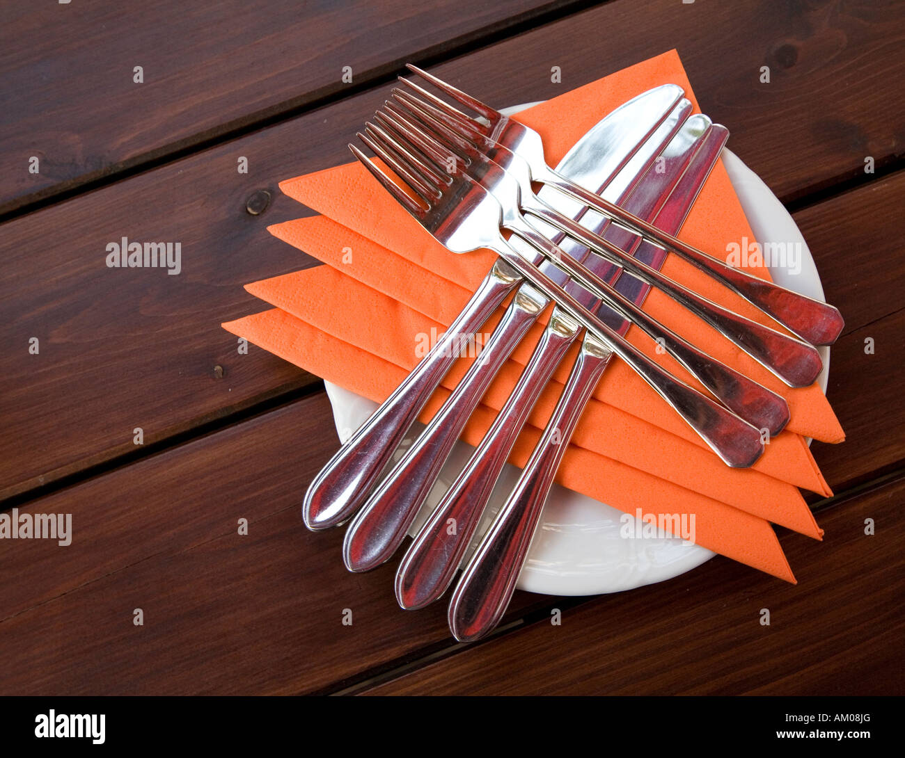 Napkins knives and forks crossed on plate ready for place setting Stock Photo