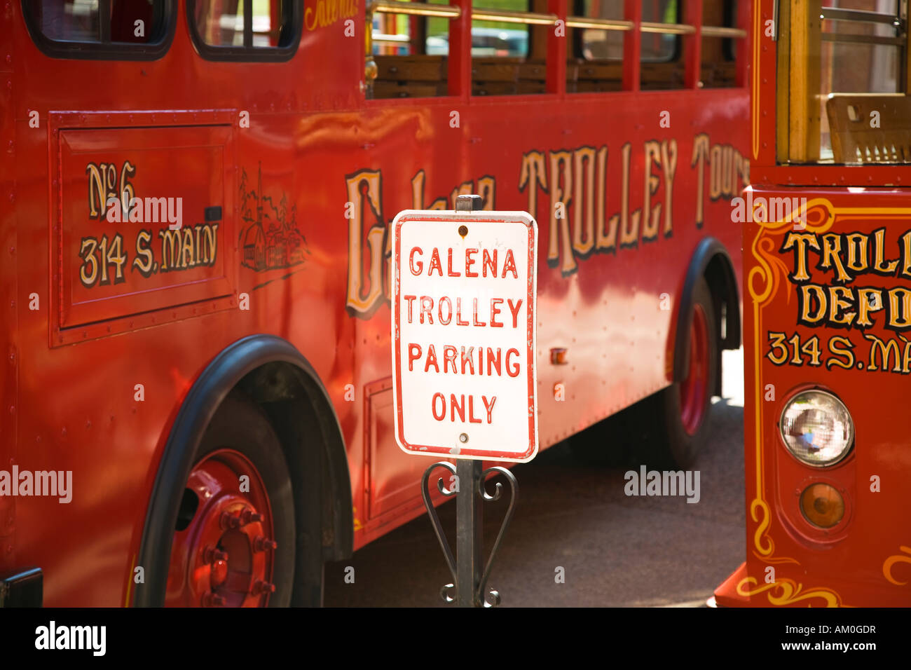 ILLINOIS Galena Sign next to two red open air trolleys for visiting
