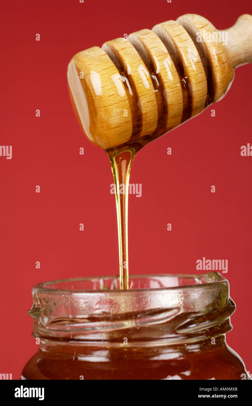 Clear honey dripping in jar from dipper Stock Photo - Alamy
