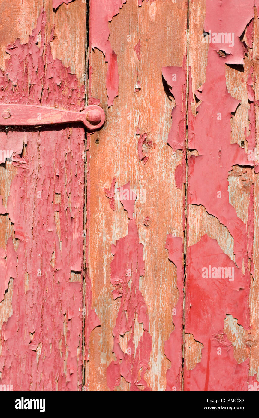 faded and peeling red paint on old wooden door Stock Photo