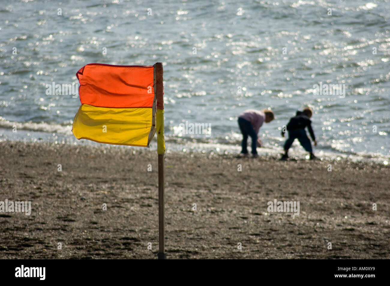 red and yellow safety flag on a beach for swimmers at the seaside Stock