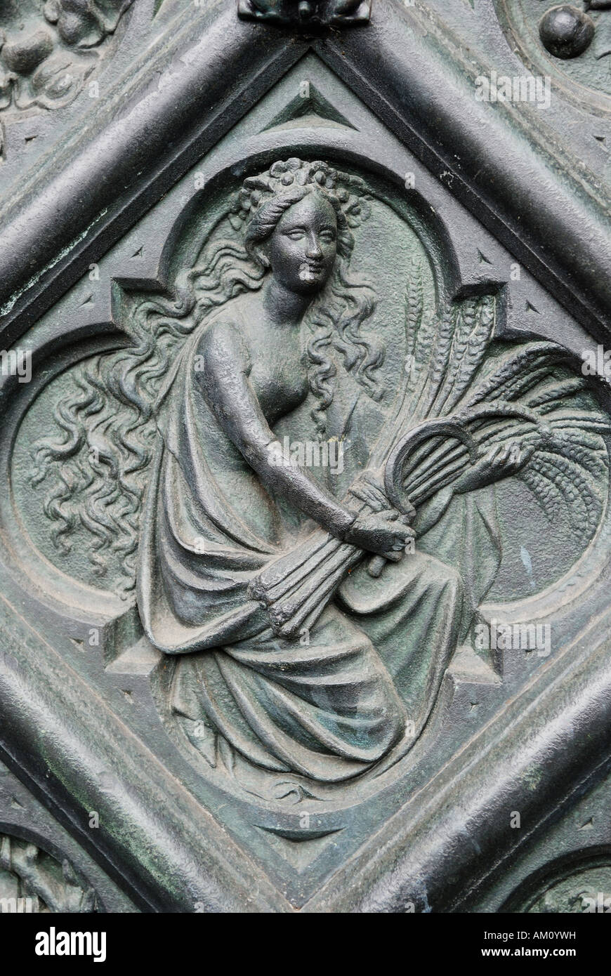 Woman with wheat ears as symbol for harvest and the season autumn: iron tile in a side portal of the cathedral of Cologne, NRW, Stock Photo