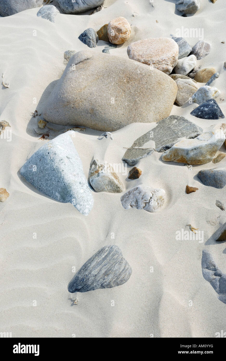 Pebbles of different geological origins polished by wind and sand laying in sand bed Stock Photo