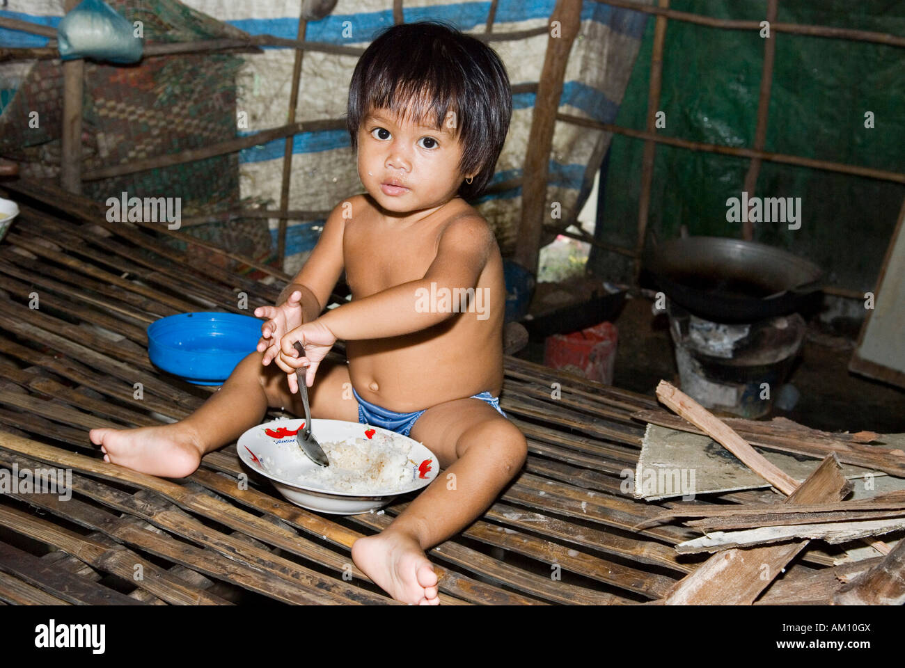 Boy eating rice in a hut in Andong slum area, Phnom Penh, Cambodia Stock Photo