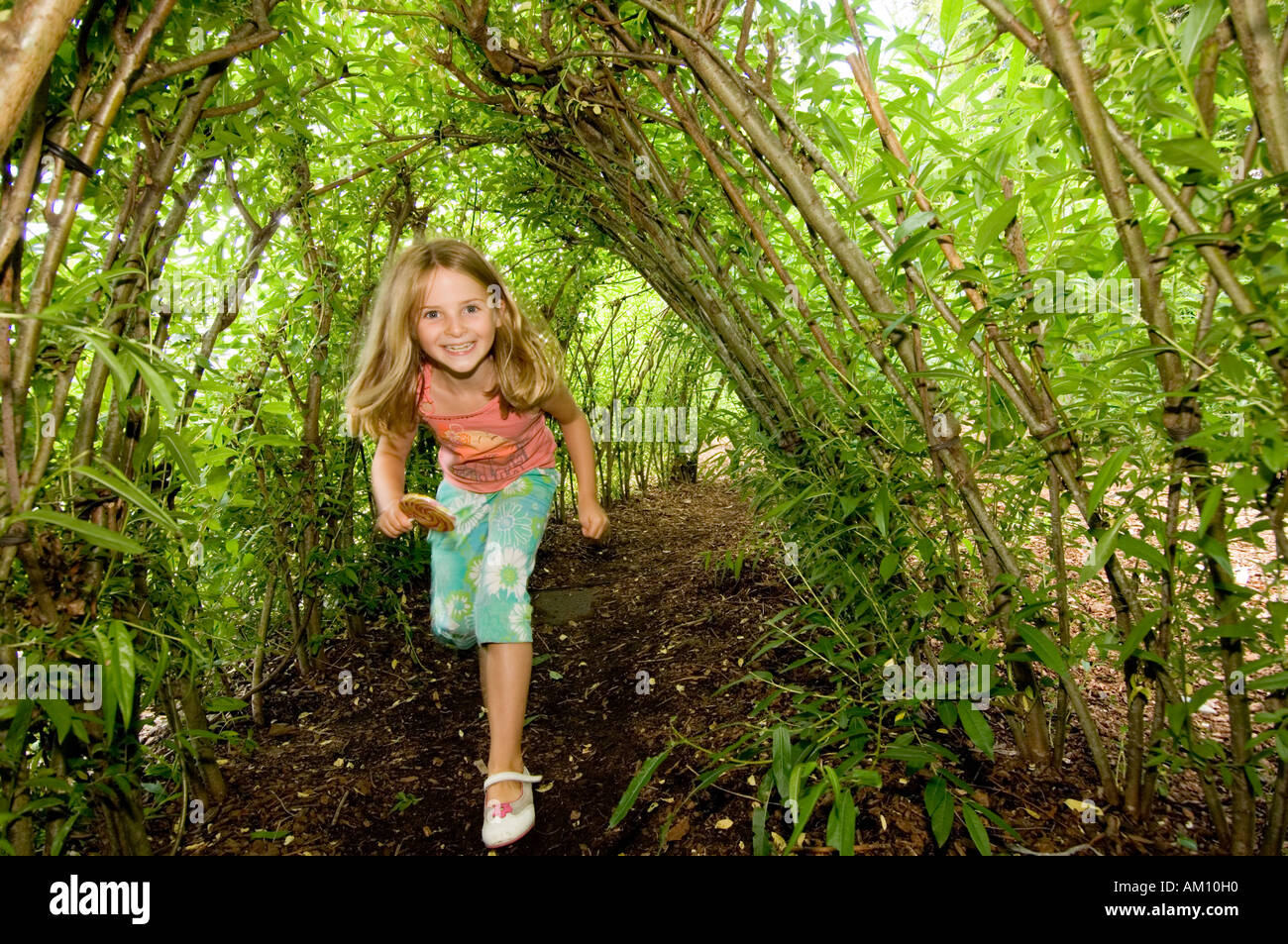 The Botanic Garden of Wales Llanarthne Carmarthen young girl playing in living green willow tunnel Stock Photo