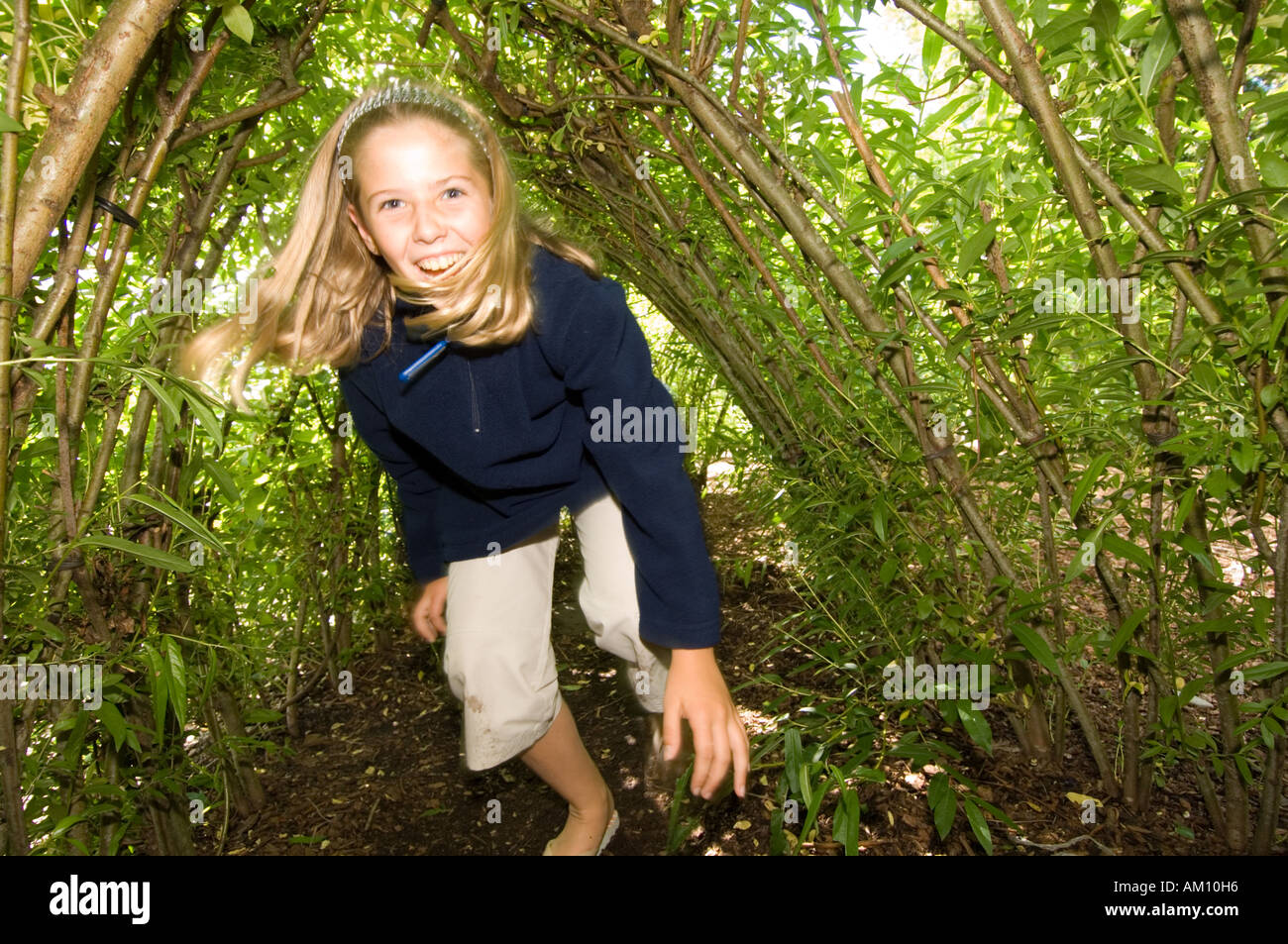 The Botanic Garden of Wales Llanarthne Carmarthen happy laughing young girl playing in living green willow tunnel, UK Stock Photo
