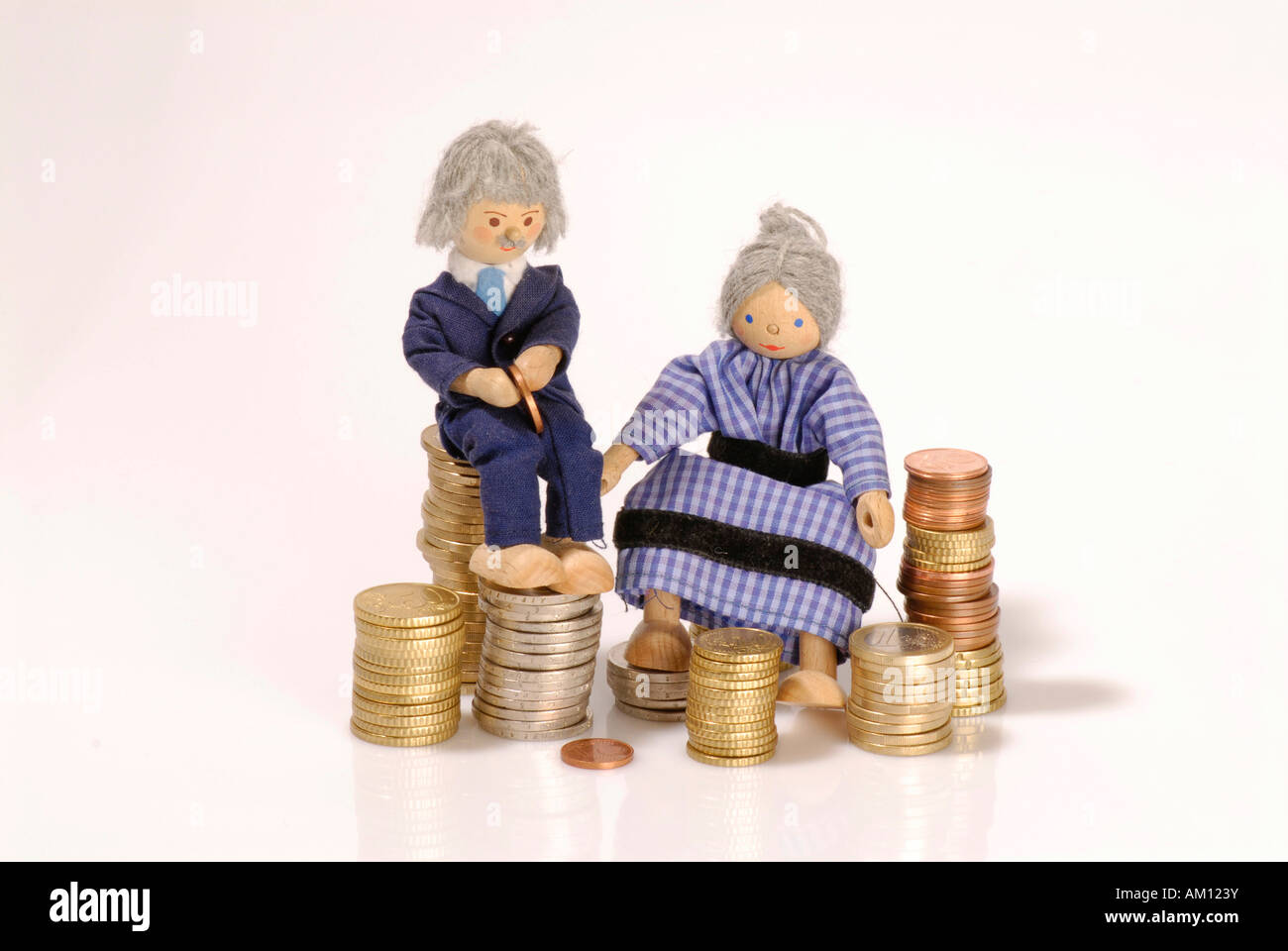 Senior dolls sitting on Euro coins Stock Photo
