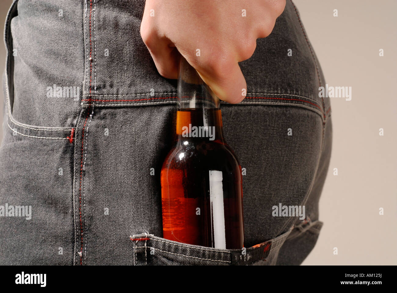 Hand pulling a bottle with alcohol out of the pocket Stock Photo