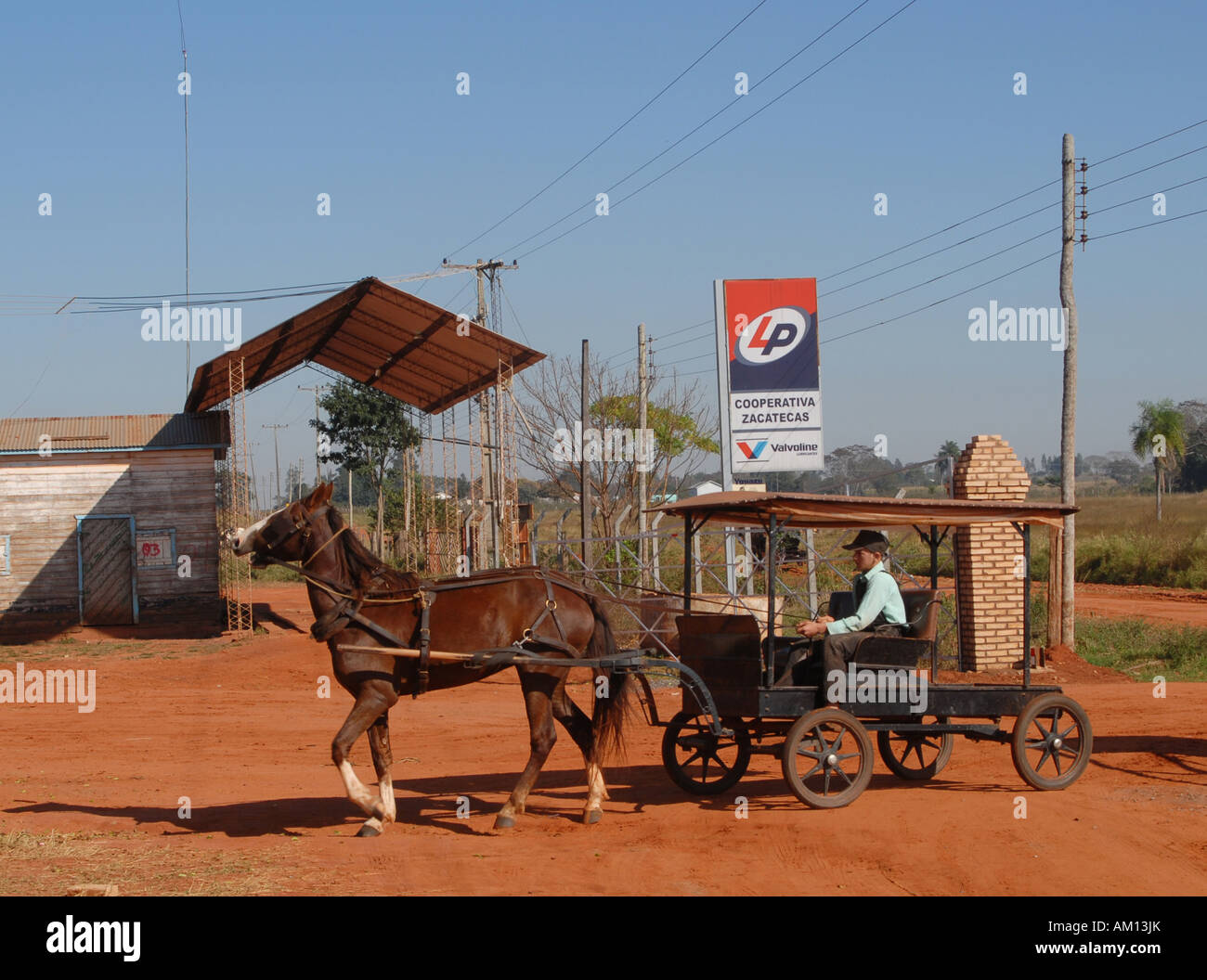 Old-style mennonites in Paraguay, boy with typical horse cart in front of a gas station Stock Photo