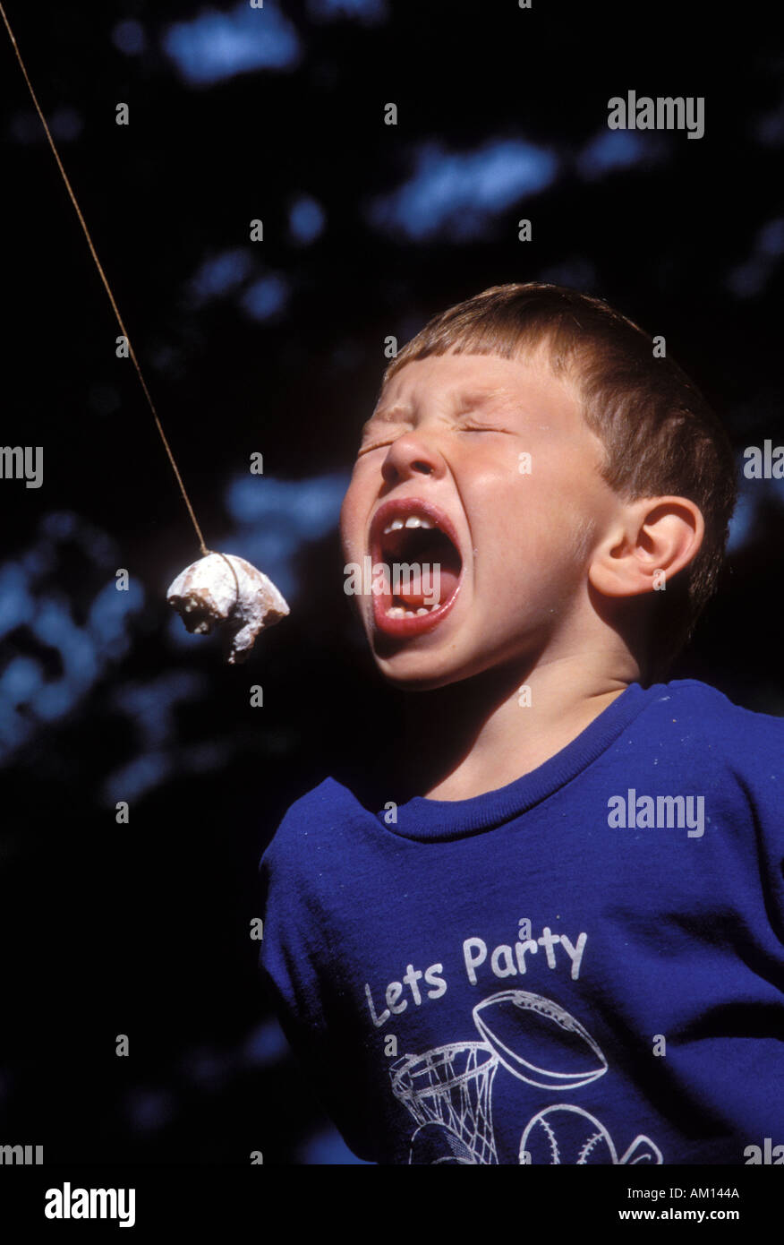 Boy Eating Donut on A String Stock Photo