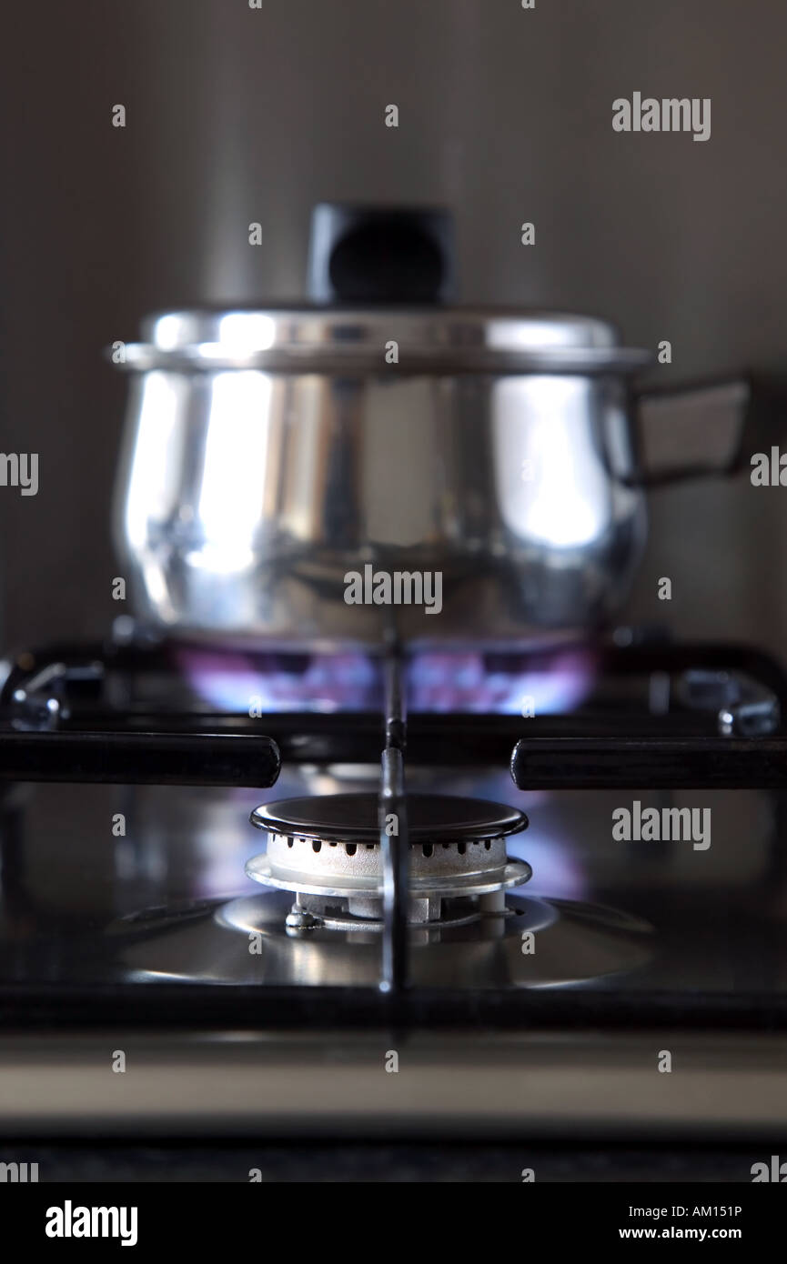Close up of a gas hob with a pan on the back burner shallow DOF Stock