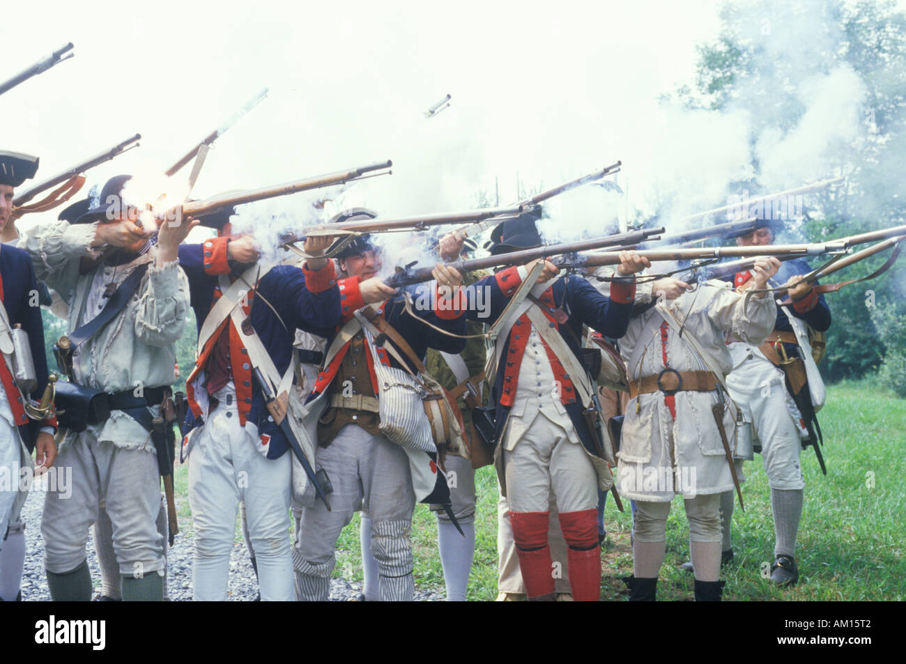 Men dressed in 18th century American military infantry costume fire muskets during reenactment of American Revolutionary War Stock Photo