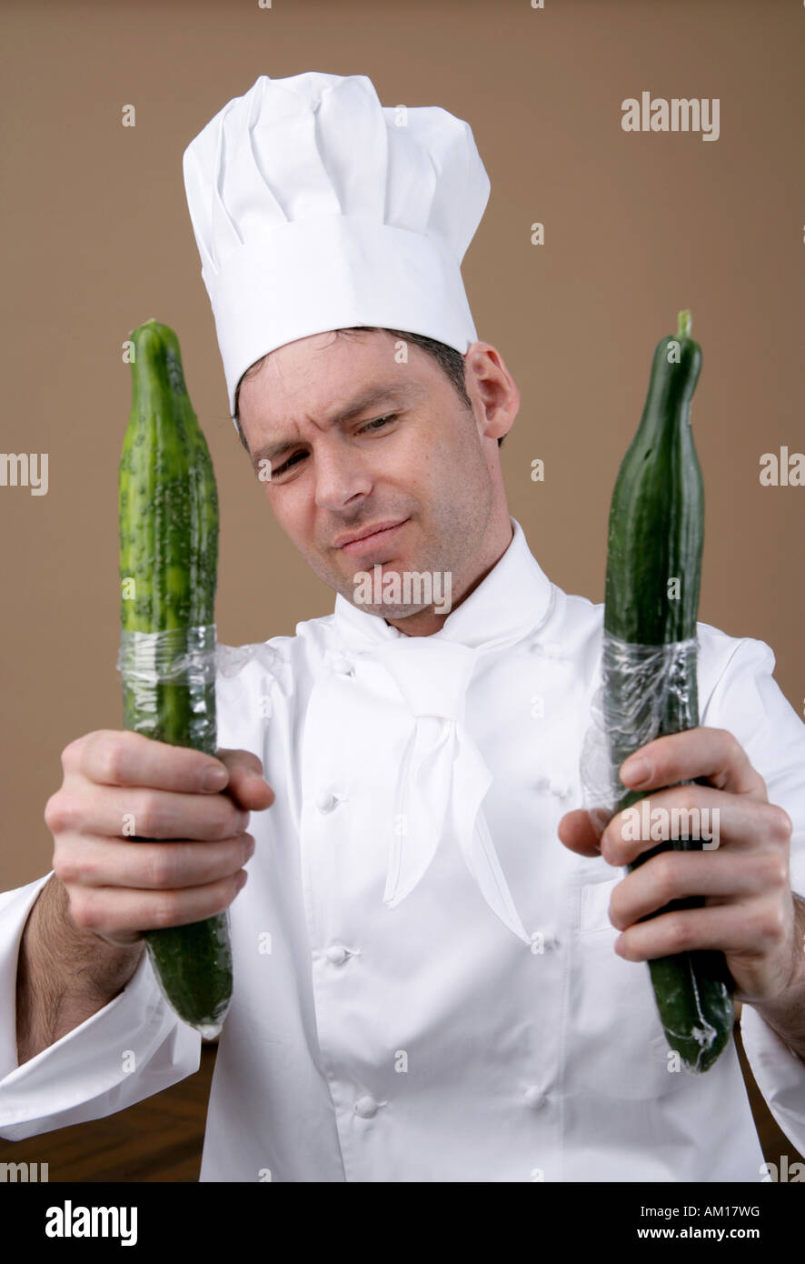 Cook looking sceptical at two cucumbers Stock Photo