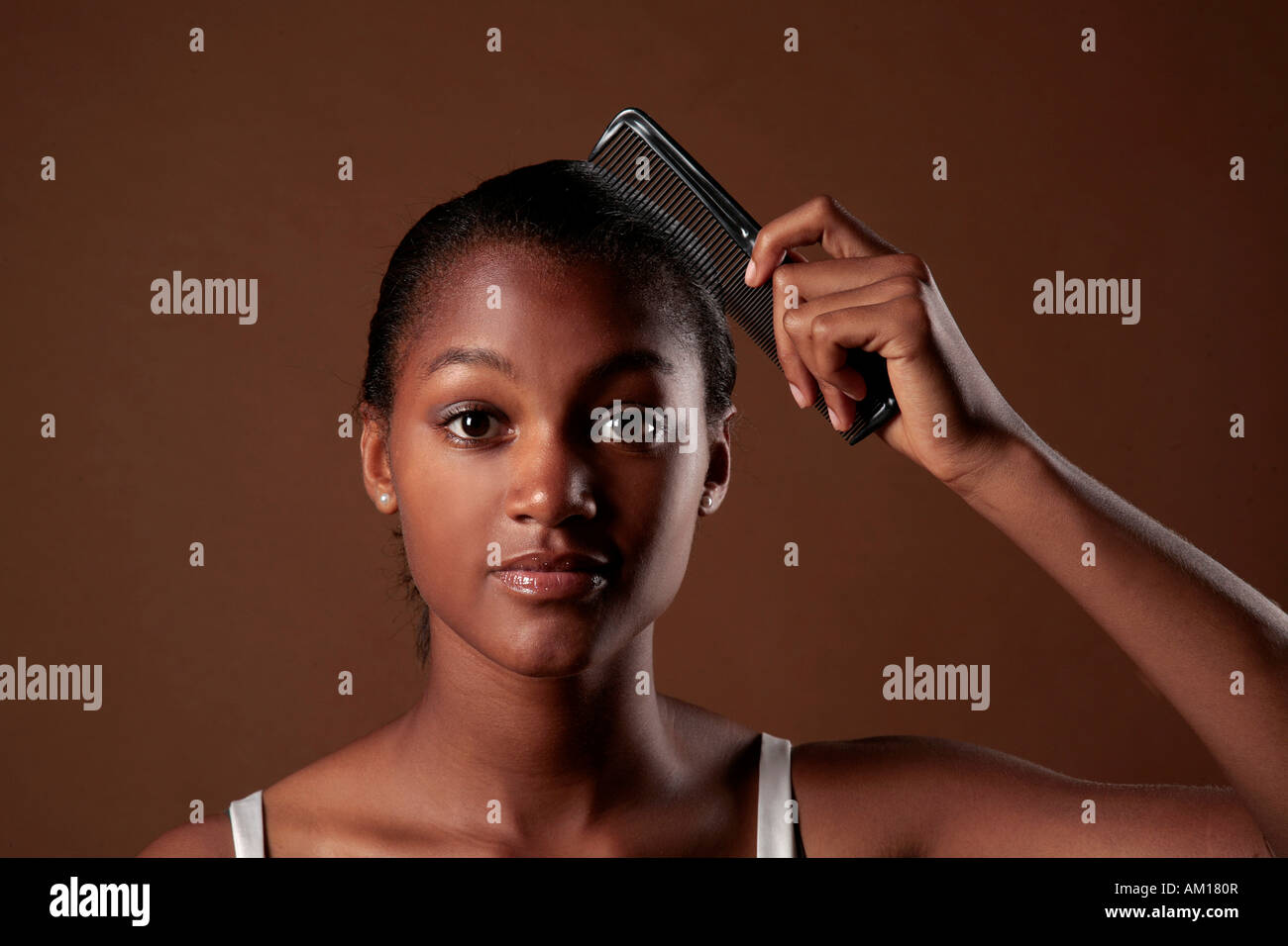 Young dark-skinned woman combing her hair Stock Photo