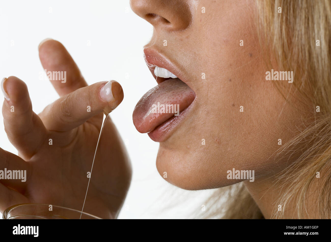 A young woman is nibbling honey Stock Photo