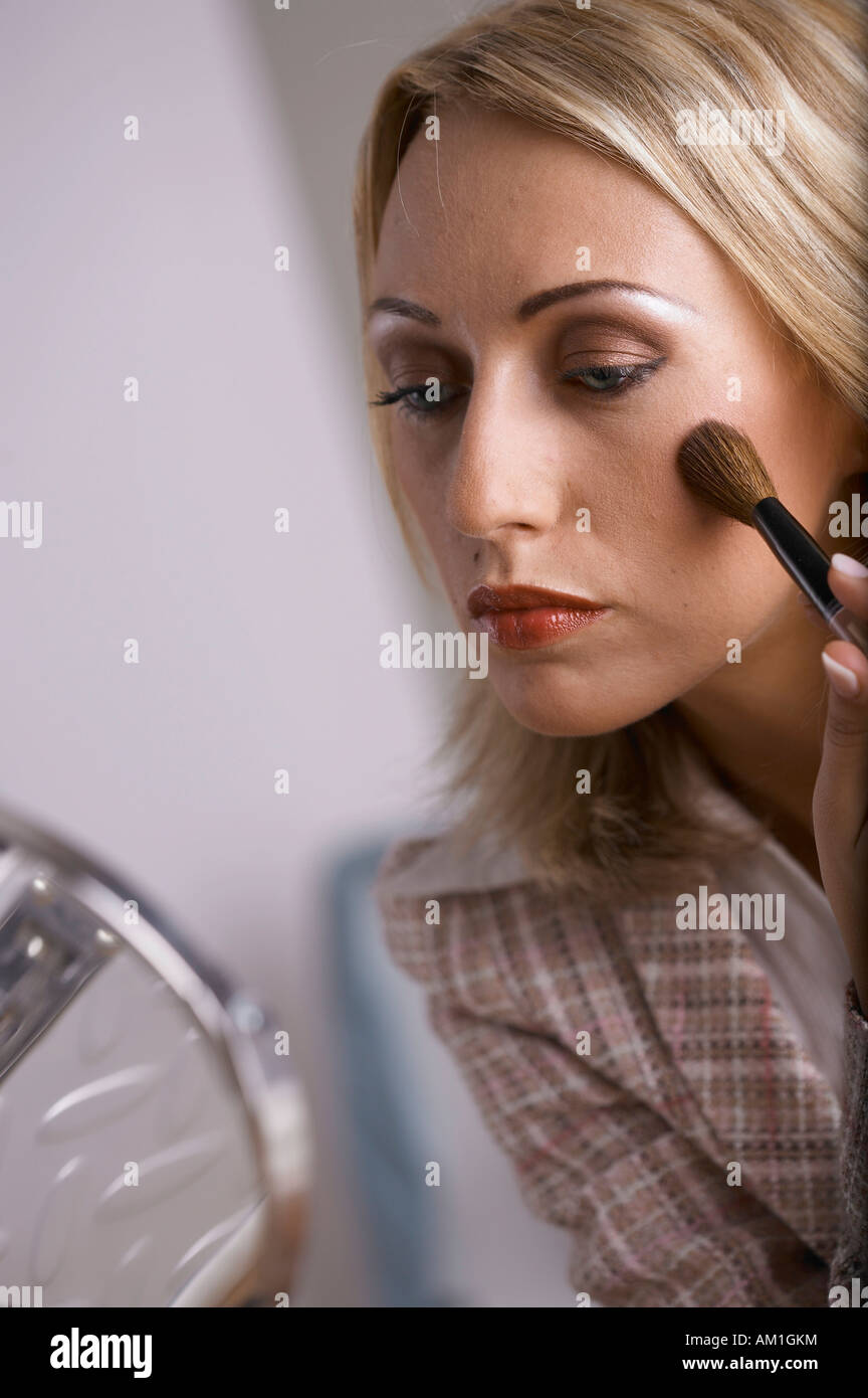 A woman lays rouge on her cheeks Stock Photo