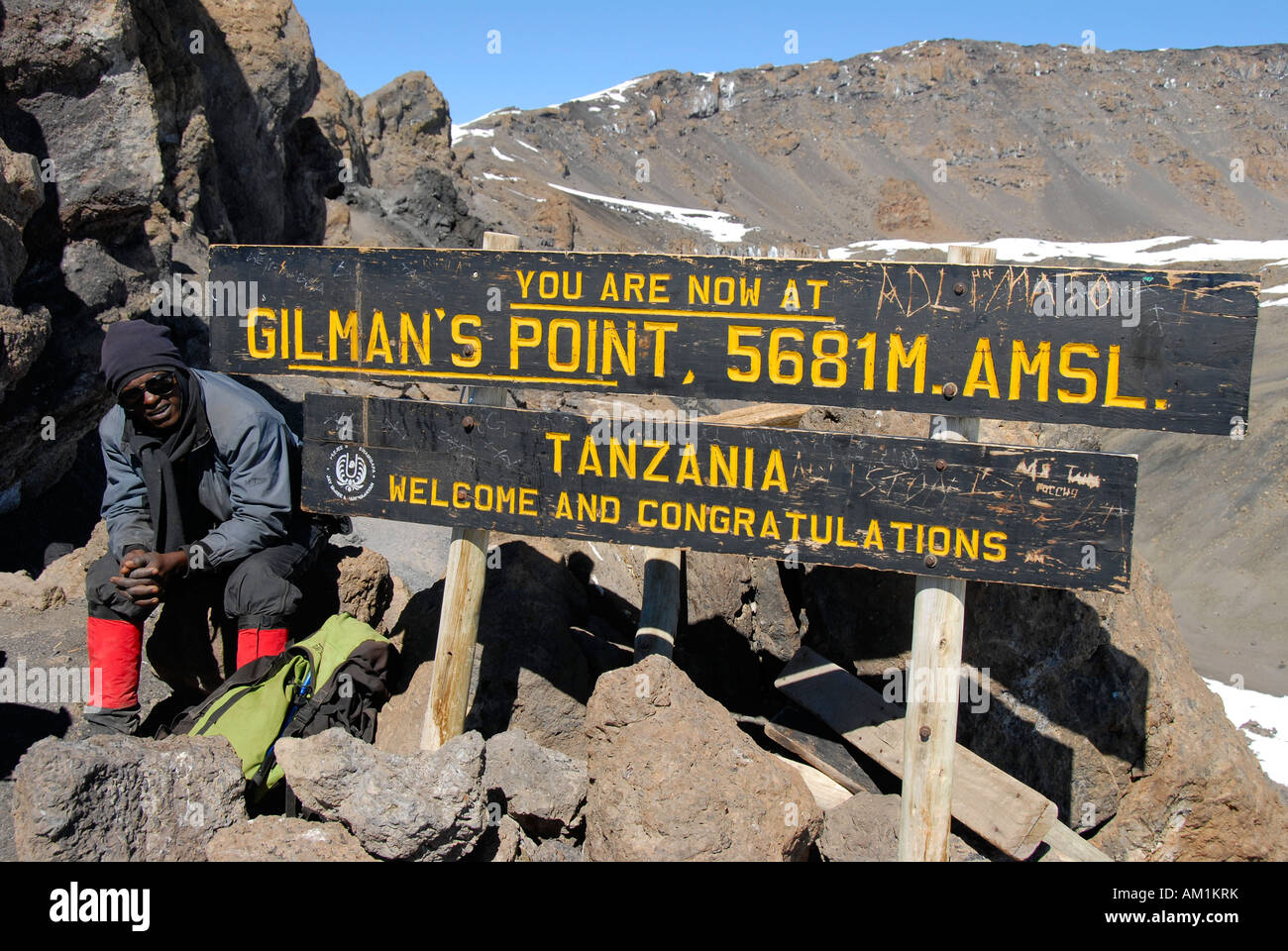 Local guide at the sign on the summit Gilman's Point (5681 m) crater rim Kilimanjaro Tanzania Stock Photo