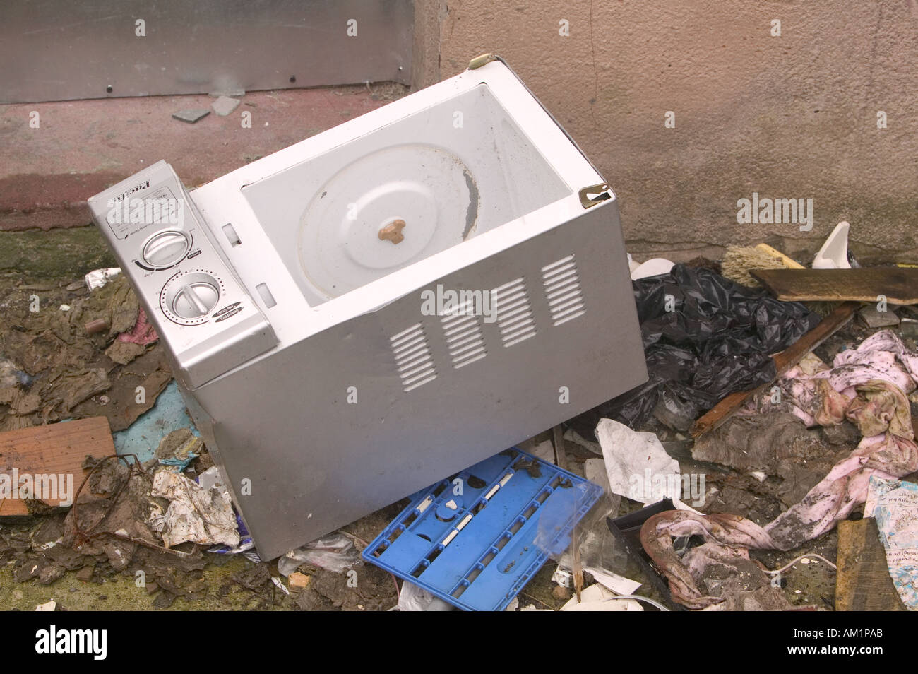 a microwave oven abandoned with rubbish in the back yard of a derelict