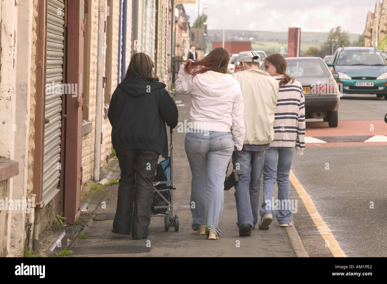 working class youngsters walking through a run down area of Burnley Lancashire Stock Photo