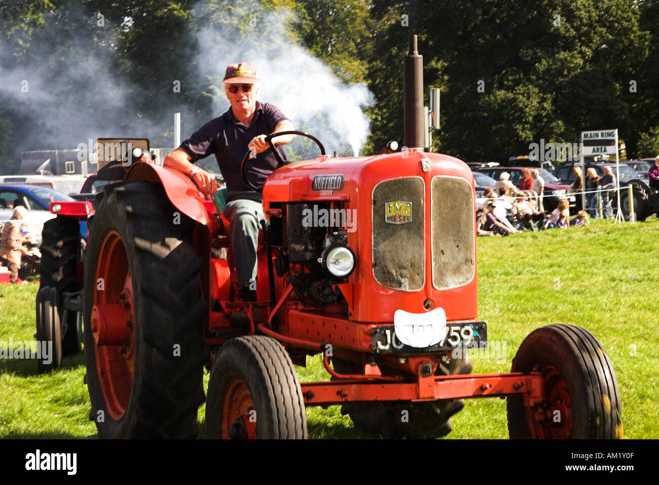 TRACTOR DRIVER A man driving a tractor while smoke billows behind Stock