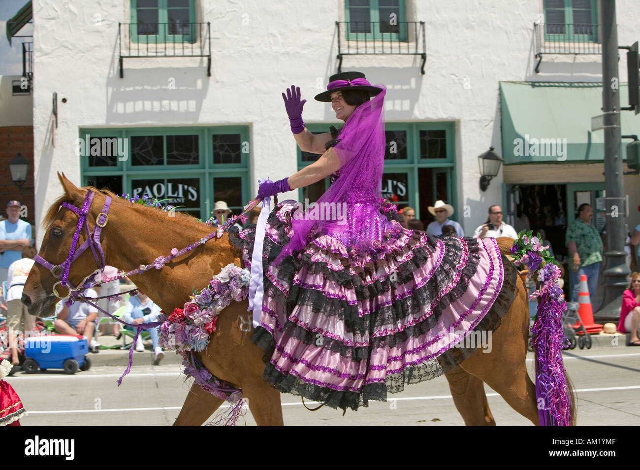 Woman with purple Spanish dress riding horse during opening day parade down State Street Santa Barbara CA Old Spanish Days Stock Photo