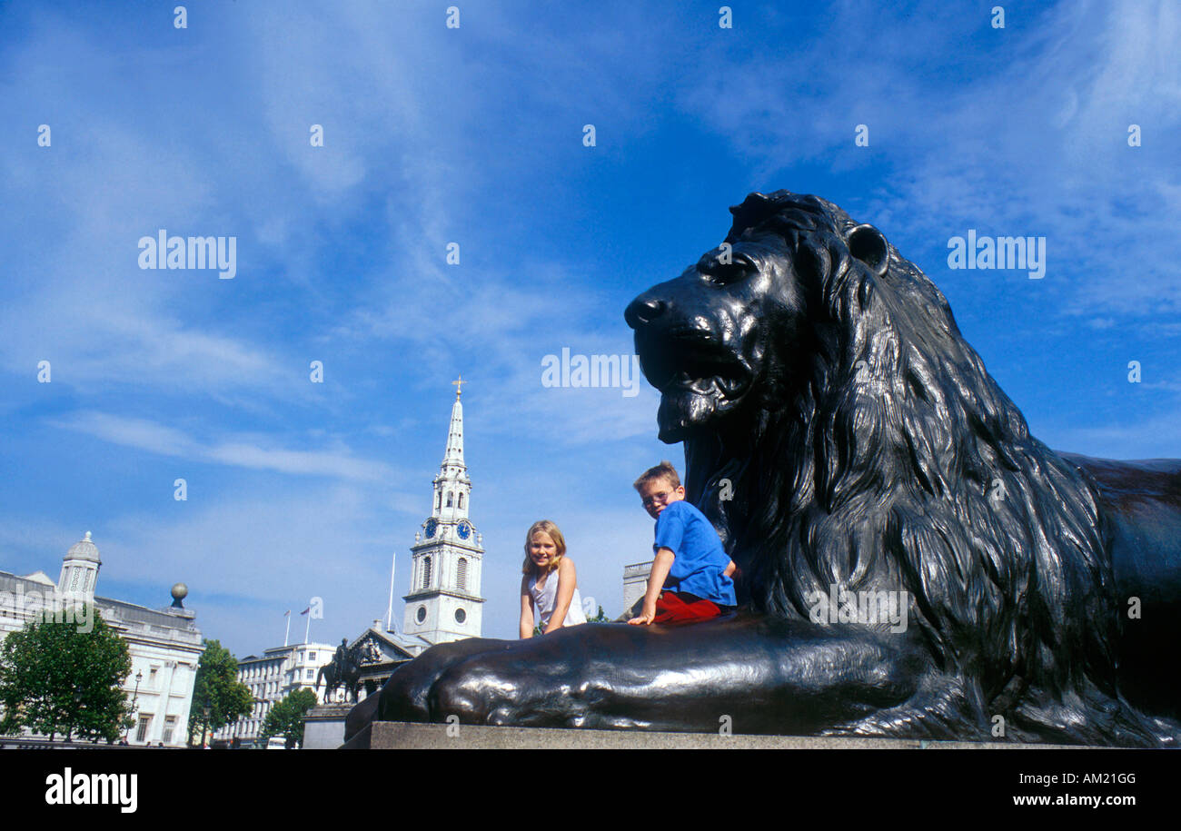 Children sitting on a Lion at Trafalgar Square in London Stock Photo