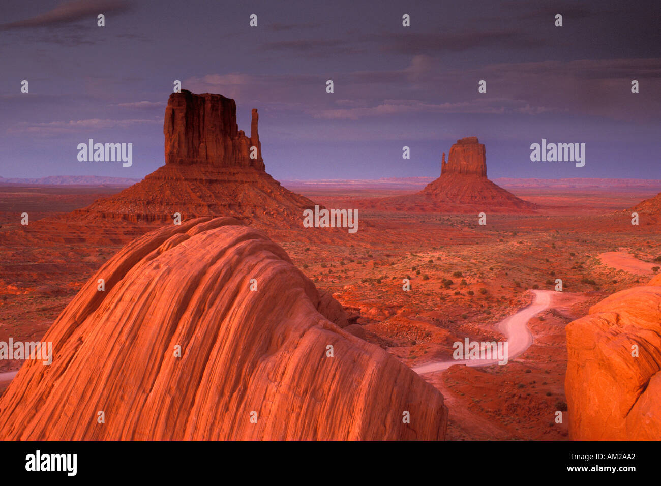 Dirt Road Red clouds sky and open flat desert at sunset Mitten Buttes