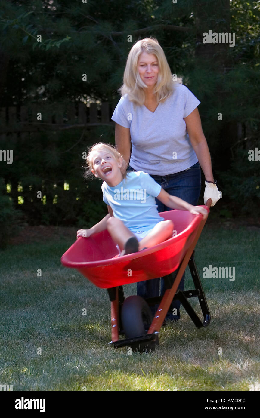 Mother carrying her daughter in a wheelbarrow Stock Photo - Alamy